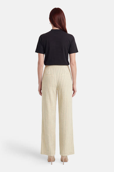 Pantalon multicolore de VILA, crème à rayures vertes verticales, coupe large, vu de dos avec un t-shirt noir et des talons beiges.