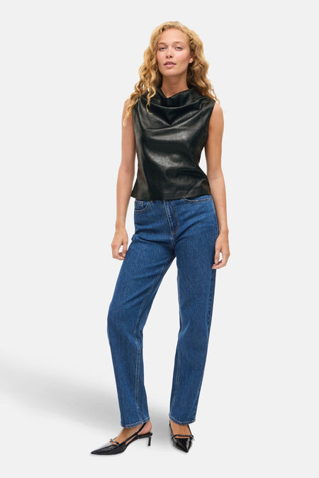 Zwart mouwloos hemd van VILA®, gedragen met een blauwe jeans en zwarte pumps.