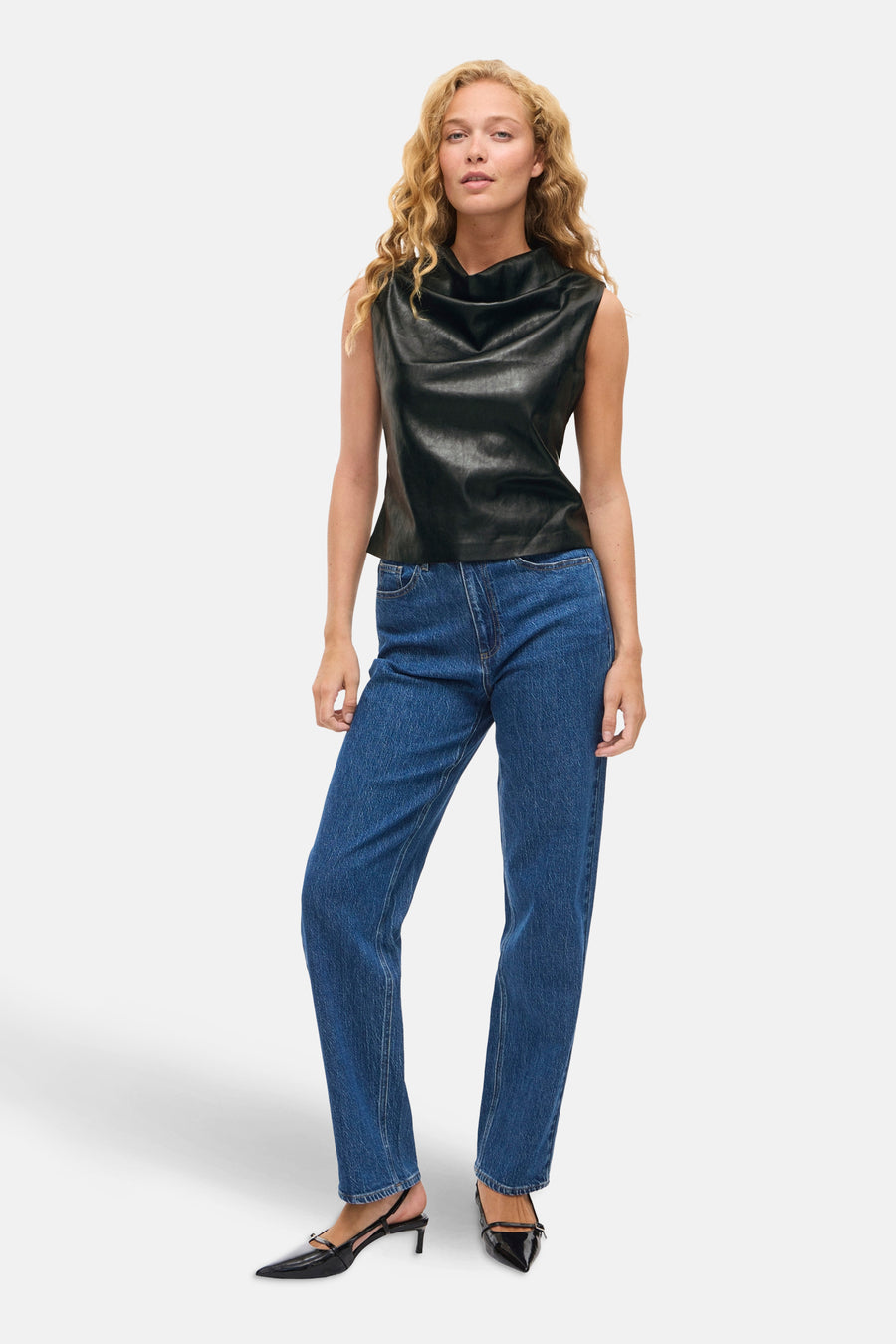 Zwart mouwloos hemd van VILA®, gedragen met een blauwe jeans en zwarte pumps.
