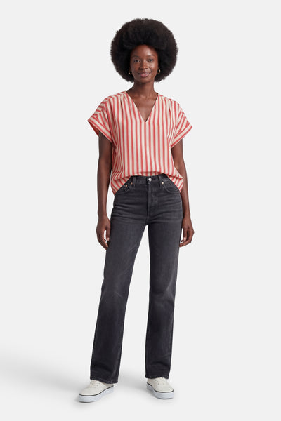 Gestreept bloesje met rode en crèmekleurige verticale strepen van VILA®, V-hals en korte mouwen, gedragen met een zwarte jeans en witte sneakers.