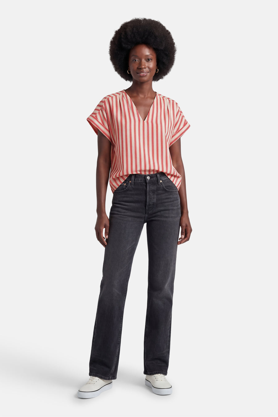 Blouse à rayures verticales rouges et crème de VILA®, col en V et manches courtes, portée avec un jean noir et des baskets blanches.