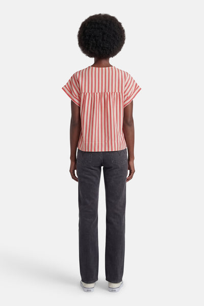 Blouse multicolore de VILA® à rayures rouges et crème, dos froncé, portée par-derrière avec un jean gris.