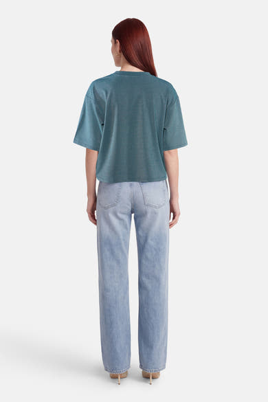 T-shirt vert scintillant de VILA®, coupe ample, porté de dos par un mannequin avec un jean clair et des talons.