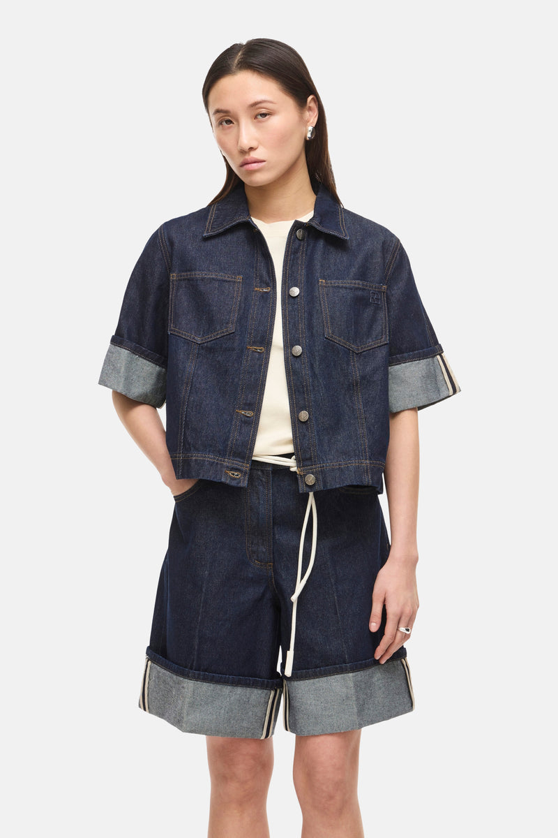 Donkerblauwe spijkerblouse van ROUGE EDIT, gedragen met een bijpassende short met trekkoord en zwarte open schoenen.