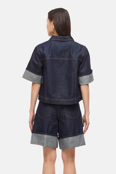 Donkerblauwe denim blouse van ROUGE EDIT, met korte mouwen met grijze omslagen en contrasterende stiksels.