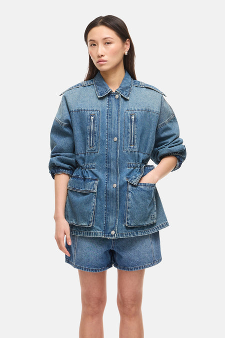 Veste courte en denim bleu moyen de ROUGE EDIT, à poches zippées et à rabat, taille à cordon, portée avec un short en jean.