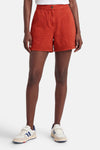 Korte oranje short van VILA® met opgestikte zakken en elastische zomen, gedragen door een vrouw met sneakers.