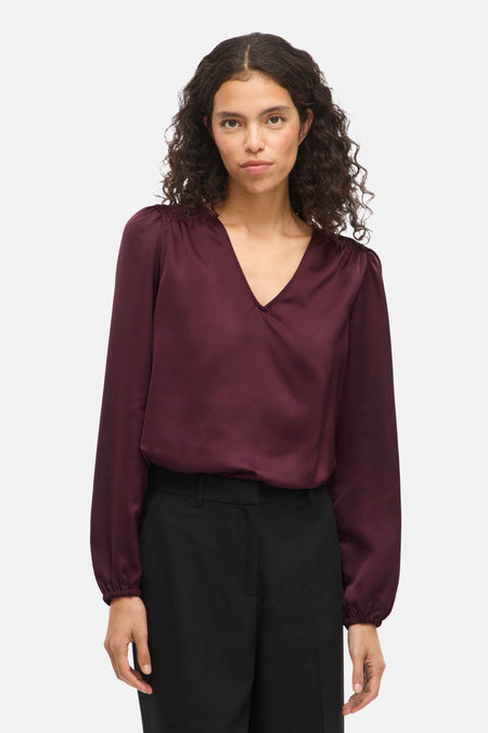 Bordeaux blouse met lange mouwen van VILA, met een V-hals en gedragen met een zwarte broek.