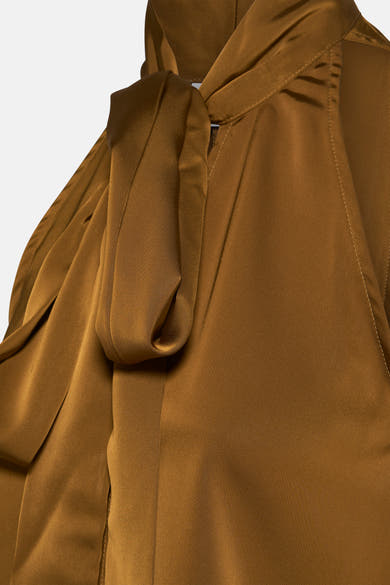 Chemisier sans manches doré de VILA®, avec un grand nœud décoratif au cou et détails de couture visibles.
