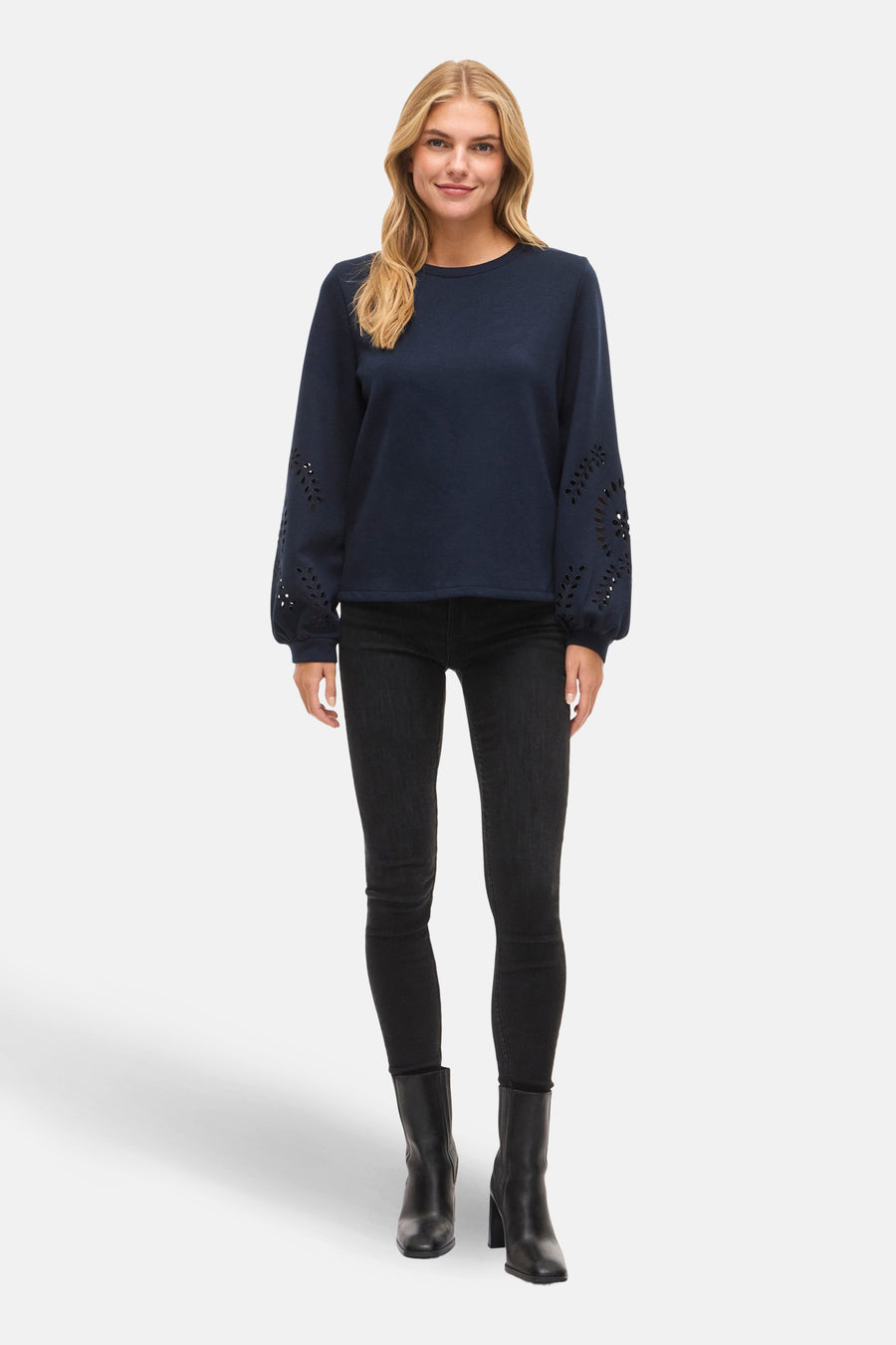 Sweat bleu van VILA®, manches longues ajourées, porté avec un jean noir et des bottines en cuir.
