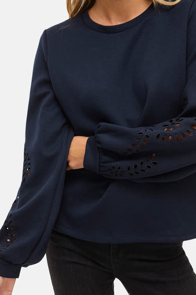 Blauwe trui van VILA, met lange pofmouwen en decoratieve uitgesneden details, gedragen met een zwarte jeans.