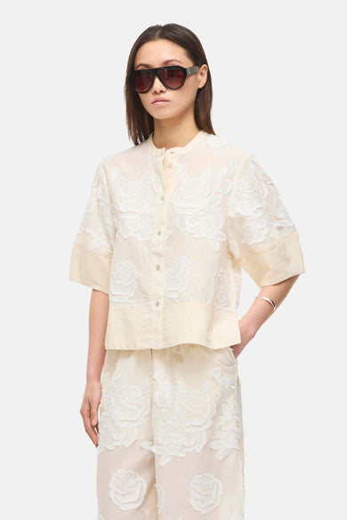 Blouse à manches courtes beige de ROUGE EDIT à broderie florale, portée avec un short assorti.