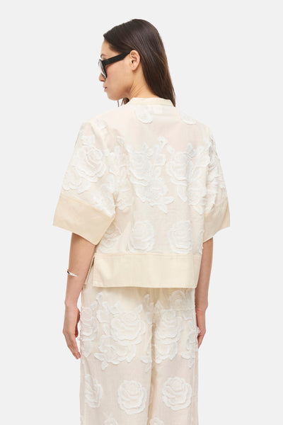 Blouse à manches courtes beige de ROUGE EDIT, ornée de broderies florales blanches en relief, vue de dos.