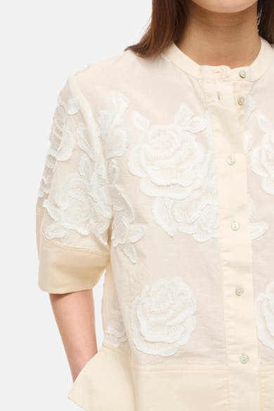 Beige blouse met korte mouwen van ROUGE EDIT met gedetailleerde witte bloemenborduursels en een knoopkraag.