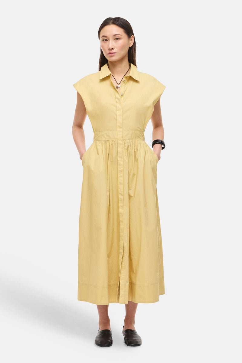 Gele midi overhemdjurk van ROUGE EDIT, mouwloos, geplooide taille, zakken en zwarte armband.