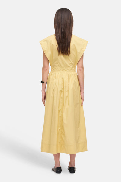 Gele jurk van ROUGE EDIT, uitlopende pasvorm, korte mouwen, geplooide taille, achterkant, gedragen met zwarte platte schoenen.