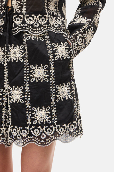 Multicolored embroidered shorts with black base and cream floral patterns, scalloped hem, side view close-up