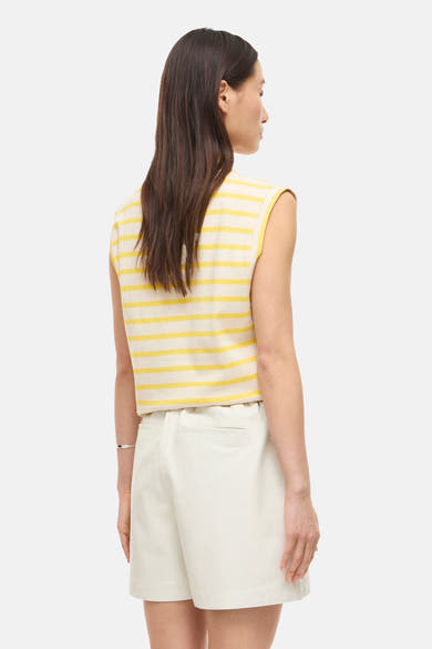 Top sans manches jaune et blanc rayé de ROUGE EDIT, vue de dos, porté avec un short écru et un bracelet.