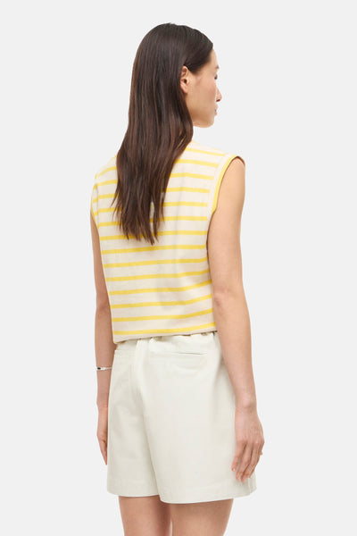 Mouwloos topje in geel en wit gestreept met ROOD EDIT, achterkant, gedragen met een ecru short en een armband.