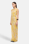 Multikleurenjurk van ROUGE EDIT, met geel en beige golvend patroon, zwart accessoire om de pols en zilveren ring.