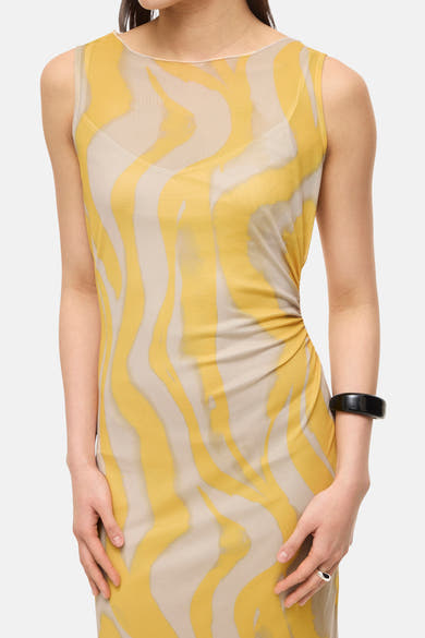 Multikleurenjurk van ROUGE EDIT, gele en beige golvende print, gedragen met een zwarte armband.