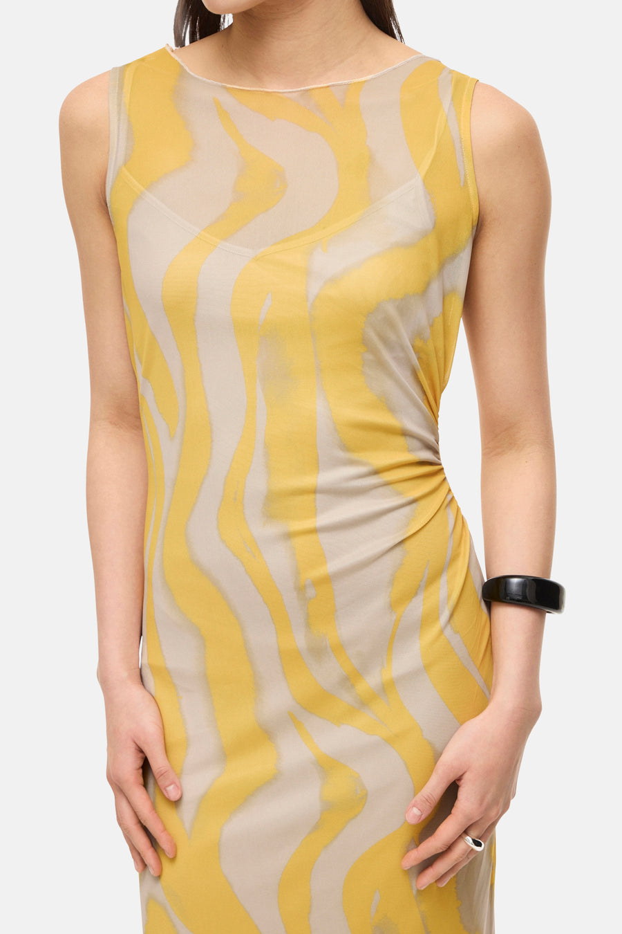 Multikleurenjurk van ROUGE EDIT, gele en beige golvende print, gedragen met een zwarte armband.