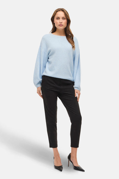 Pull à col rond bleu de VILA®, orné de perles discrètes, porté avec un pantalon noir et des escarpins noirs.
