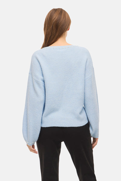 Blauwe trui met ronde hals van VILA, versierd met kralen bij de halslijn en mouwen, gedragen met een zwarte broek.