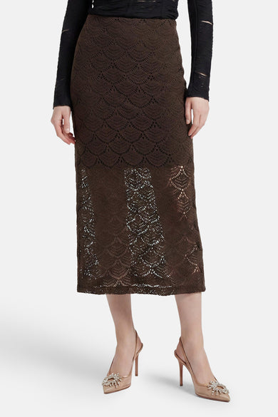 Brown lace long skirt with scalloped pattern, worn with black top and nude heels, front view