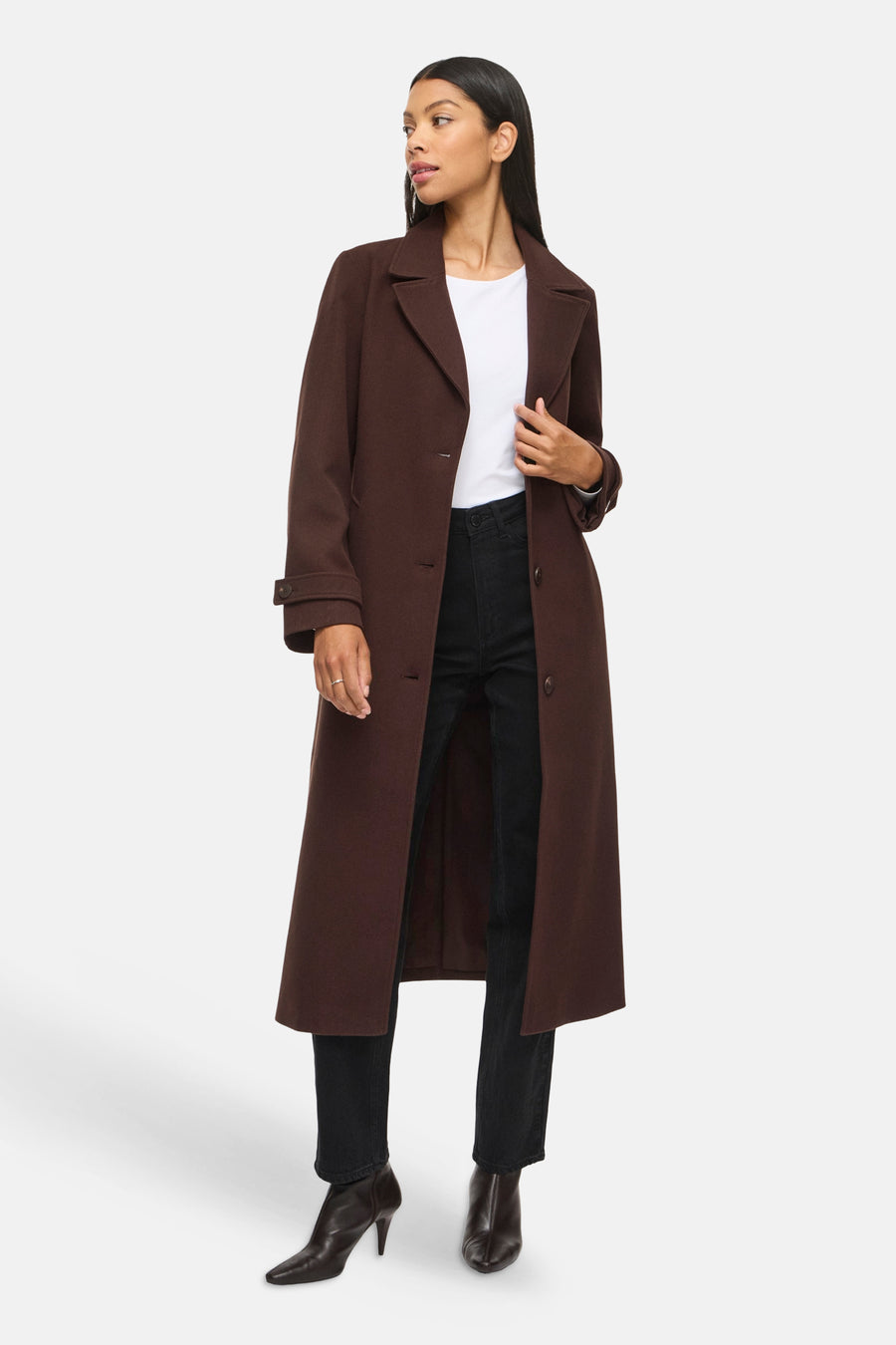 Veste longue brun foncé VILA® portée par un mannequin, avec revers crantés et manches longues.