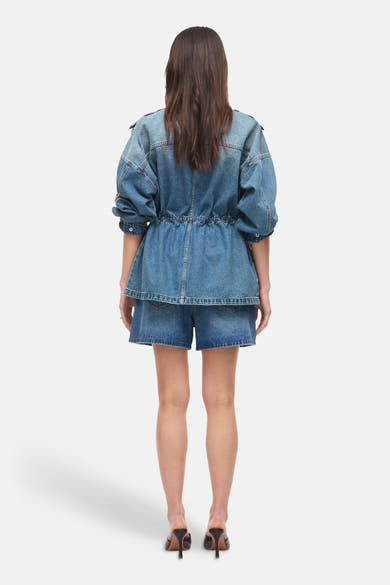 Short en jean bleu moyen de ROUGE EDIT, porté avec une veste en denim et des talons, vue de dos.