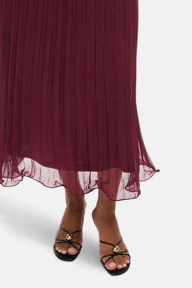 Jupe longue bordeaux de VILA®, plissée avec ourlet transparent, portée avec des sandales noires.
