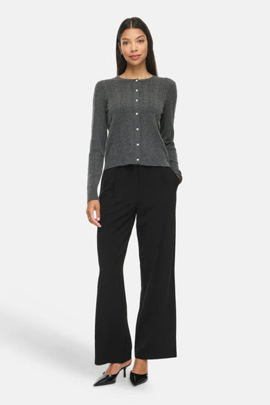 Dark grey melange cable-knit gilet with front buttons, worn with black wide-leg trousers and pointed heels, full-length front view