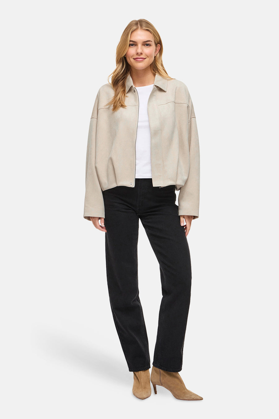 Veste courte beige de VILA, portée avec un t-shirt blanc et un jean noir avec des bottines couleur sable.
