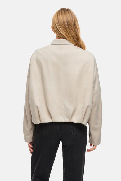 Veste courte beige de VILA®, vue de dos, avec texture douce et pantalon noir visible.
