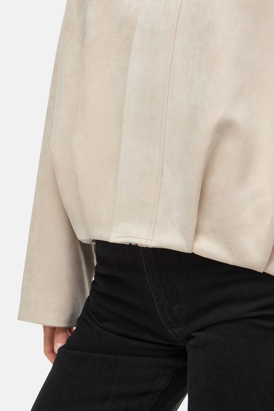 Veste courte beige de VILA, détails structurés sur tissu doux, portée avec un pantalon noir.
