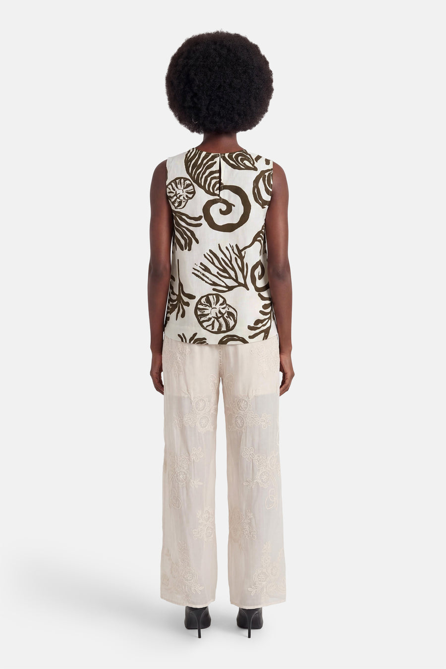 Blouse sans manches écru à motifs marins bruns de VILA®, vue de dos, portée avec un pantalon brodé.