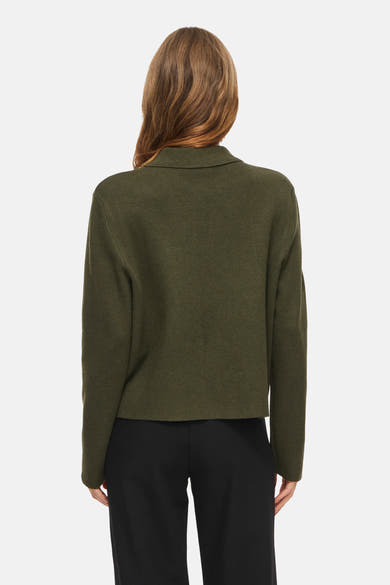 Olive green ribbed cardigan with stand collar, back view, worn with black trousers