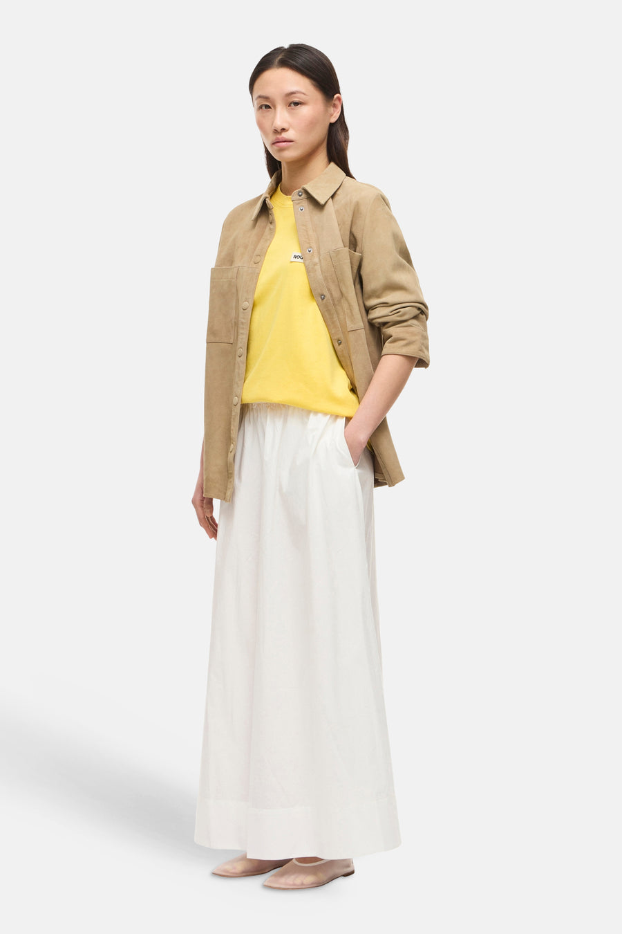 Jupe longue blanche de ROUGE EDIT, ample et fluide, portée avec un t-shirt jaune et une veste camel.
