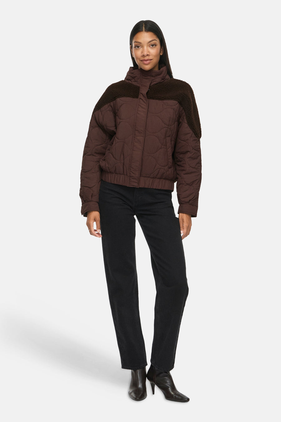 Veste courte marron matelassée par VILA® avec col montant et détails en fausse fourrure sur les épaules, portée avec jeans noirs et bottines.