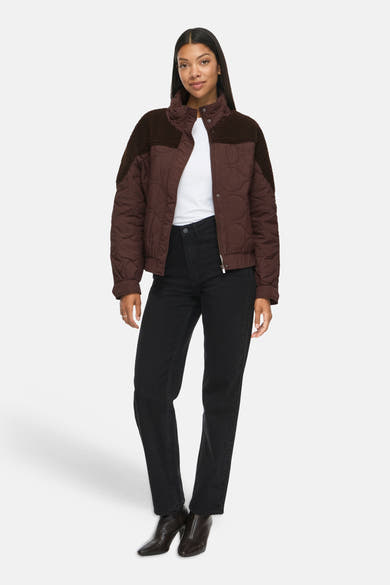 Veste courte marron matelassée par VILA®, col et épaules en fausse fourrure, portée avec t-shirt blanc et jeans noirs, vue de face.
