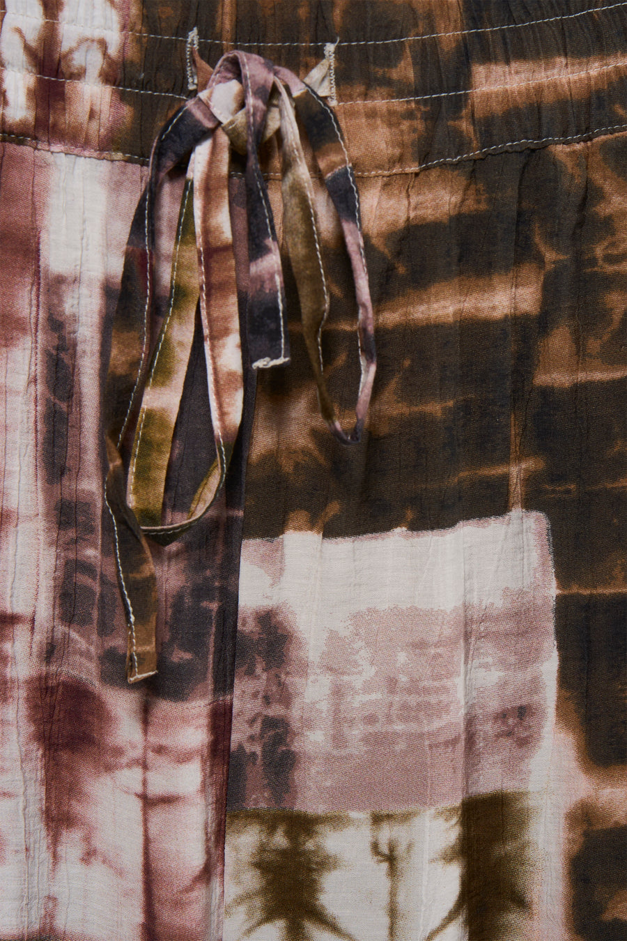 Multicolored tie-dye pants with elastic waist and matching drawstring, close-up front view