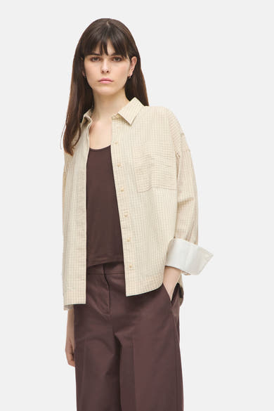 Beige long-sleeve checkered shirt with button front and chest pocket, worn open over dark top and brown trousers, front view
