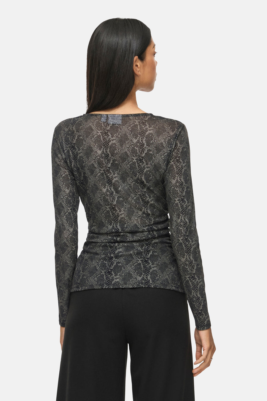 Black long-sleeve T-shirt with snakeskin print and ruched waist, back view, worn with black pants