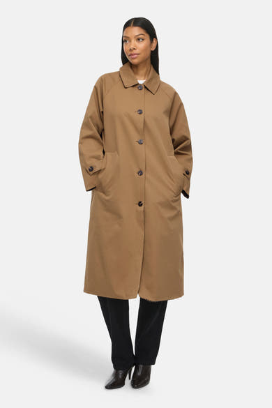 Modèle portant un trench brun VILA® à col rabattu, fermeture boutonnée et poches latérales.