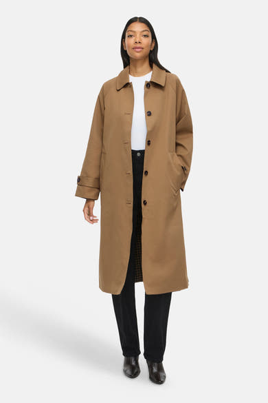 Femme portant un trench brun VILA® sur un top blanc et un pantalon noir