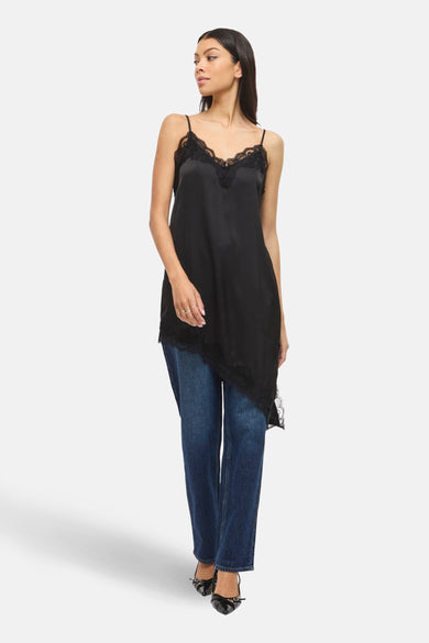 Robe noire de VILA®, avec dentelle, portée sur un jean bleu et des escarpins noirs.
