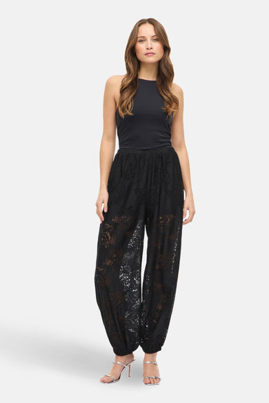 Zwarte broek van VILA® in bloemenkant, casual stijl met een effen zwart topje en zilveren hakken.