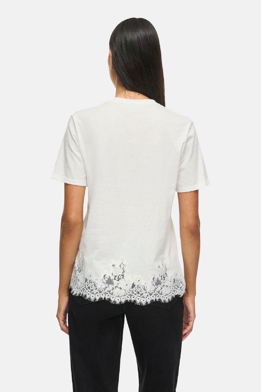 Top blanc à manches courtes avec bordure en dentelle au bas, de VILA®, vue arrière sur modèle portant un pantalon noir