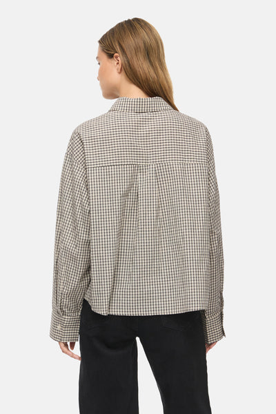 Long-sleeve checkered blouse in beige and black by Birch, back view with relaxed fit and buttoned cuffs, paired with dark pants